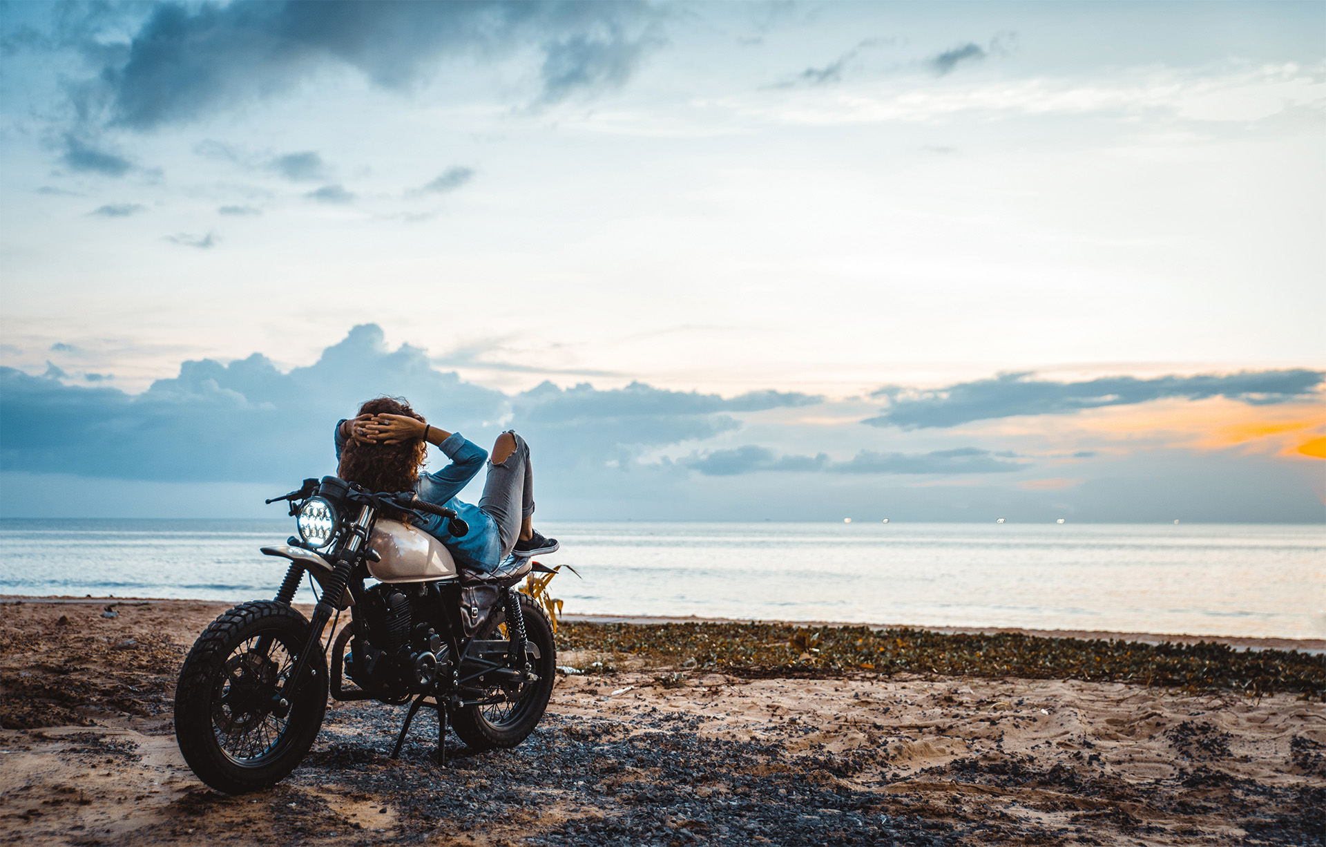 Eine Person sitzt auf einem Motorrad am Strand.