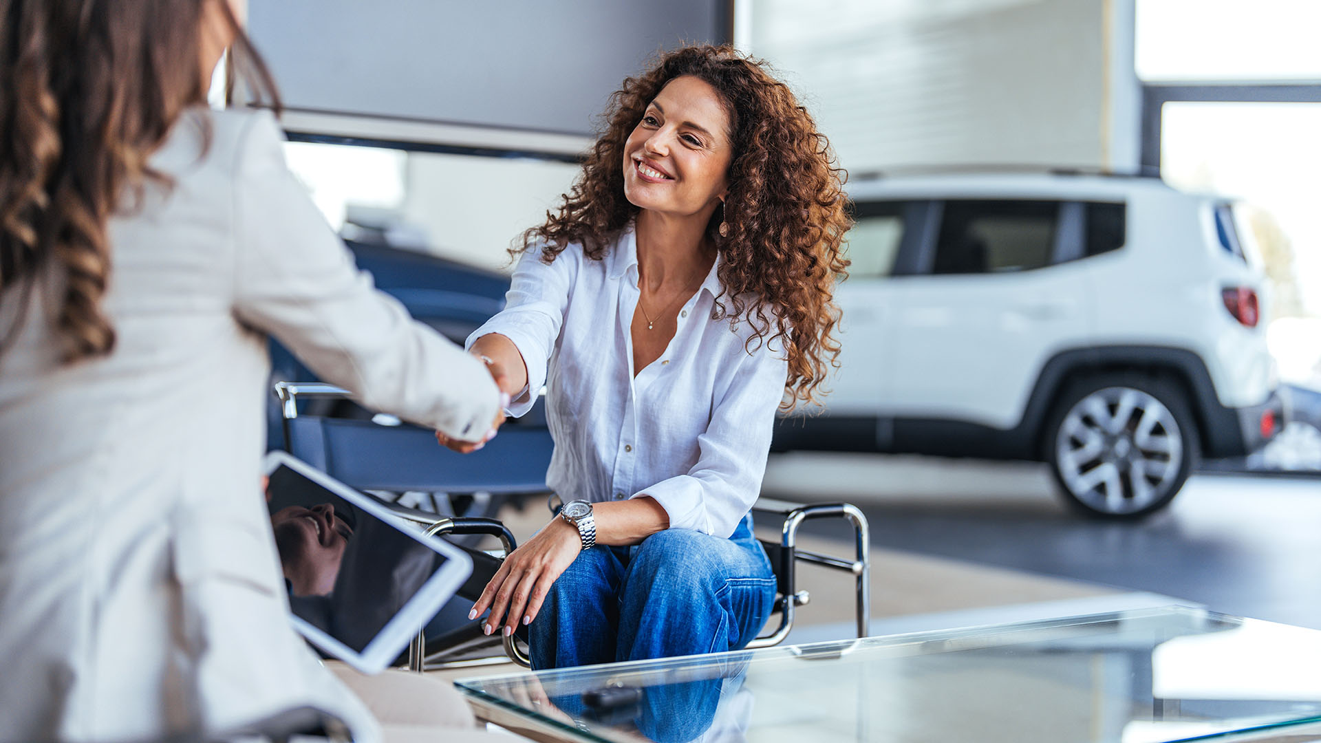 Zwei Frauen schütteln sich im Autohaus die Hand.